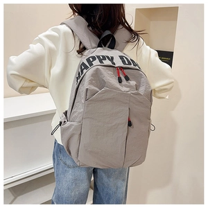 Detail of grey nylon backpack featuring HAPPY DAY print and red functional zipper pullers