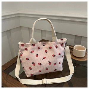 Detailed shot of pink corduroy tote bag featuring strawberry print and metal snap closure