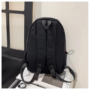 Detail of wide adjustable straps and waterproof nylon texture on black backpack