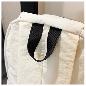 Top detail of large nylon backpack featuring a reinforced black webbing carry handle