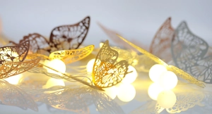 Dettaglio di luci LED a farfalla bianco caldo con trame metalliche cave intricate