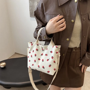 Bolso tote de pana blanca con estampado de fresas y correa ajustable en una modelo