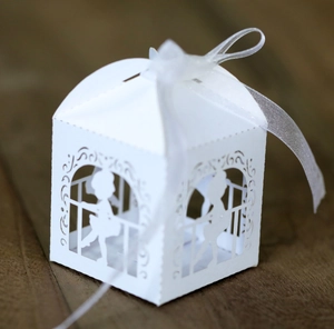 Détail d'une boîte cadeau blanche découpée au laser avec motifs de vigne et ruban
