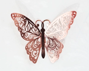 Detailed macro view of laser-cut rose gold metal butterfly with intricate swirl textures