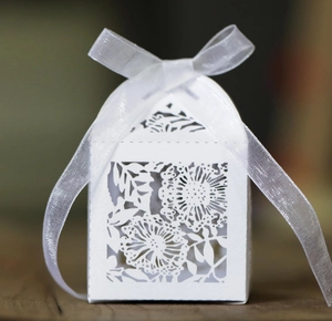 Laser cut floral wedding favor box in white paper with elegant ribbon bow detail