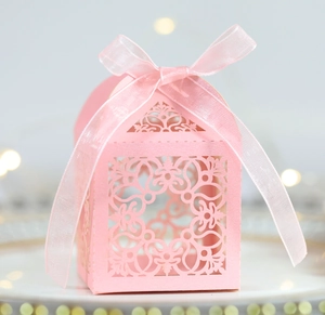 Détails de découpe laser sur une boîte à bonbons rose en forme de maison avec ruban