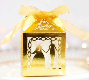 Elegant gold laser-cut wedding candy box with couple silhouette and silk ribbon bow