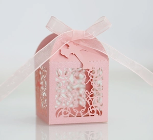 Pink laser-cut candy box with cross pattern and ribbon for wedding ceremonies