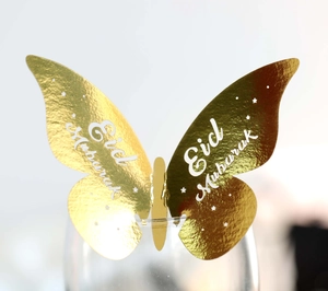 Detail of gold butterfly glass card with Eid Mubarak cutout on transparent cup