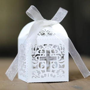 Detailed view of white laser-cut favor box with cross pattern and sheer organza ribbon bow