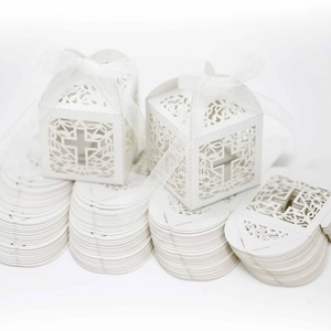 Cajas blancas cortadas por láser con diseño de cruz y cinta de organza para celebraciones