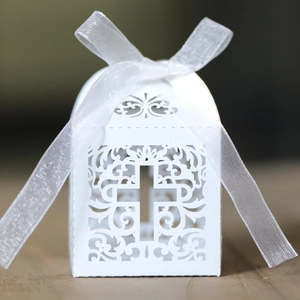 Detail of laser cut white hollow cross pattern on wedding candy box with satin ribbon bow