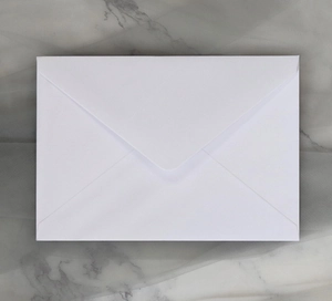 Flat lay of white paper envelope with V-flap design on grey marble background