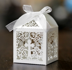 Vue macro d'une boîte à dragées blanche découpée au laser avec motif croix et ruban