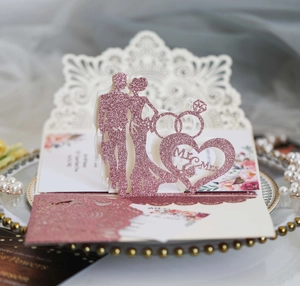 Close-up of laser cut rose gold glitter wedding invitation with Mr & Mrs silhouette