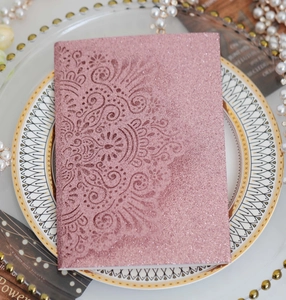 Detailed view of pink glitter laser cut wedding invitation with mandala pattern and pearls
