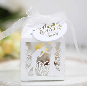 Close-up of laser-cut white wedding favor box with ribbon and thank you tag