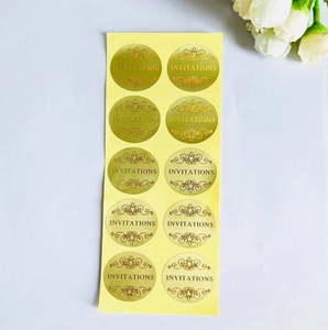 Close-up of 10 gold oval wedding invitation seal stickers with elegant embossed scroll patterns