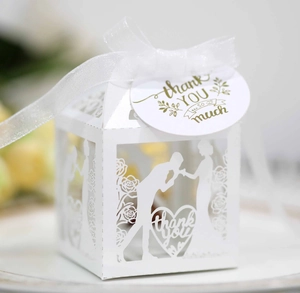 Close-up of laser-cut wedding favor box with bride and groom silhouette and ribbon
