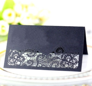 Elegant laser cut black wedding place cards with intricate floral patterns for guest seating