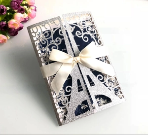 Detailed laser-cut Eiffel Tower invitation with elegant silver glitter and a silk bow