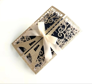 Intricate laser-cut gold glitter wedding invitation card with elegant ivory satin ribbon