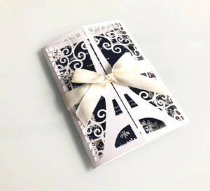 Detail of laser cut Eiffel Tower invitation with silk ribbon bow and blue insert card