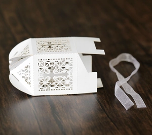 Elegant white laser-cut hollow gift box with cross pattern and white ribbon for weddings