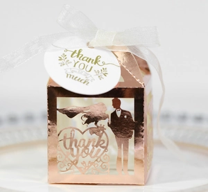 Rose gold laser-cut wedding favor box with bride groom silhouette and white ribbon tie