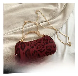 Detail of burgundy leopard print evening clutch with gold circular handle and pearl clasp