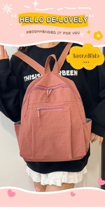 Detail of water-resistant nylon backpack in coral pink worn by a model against white wall