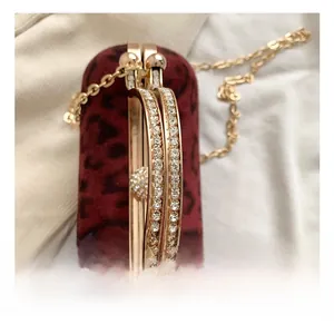 Detail of red leopard velvet handbag featuring diamond-encrusted gold metal handle