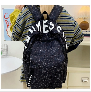 Detail of black splatter pattern backpack with large white letters and nylon strap