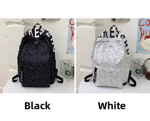 Detail of black and white canvas backpacks featuring colorful paint splatters and straps
