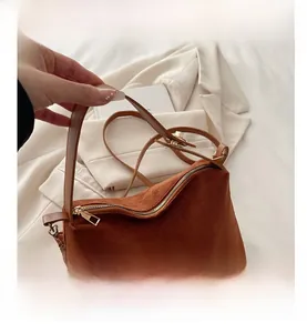 Detail shot of brown faux suede handbag with gold zipper and adjustable buckle strap