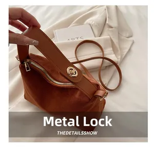 Close-up of golden metal lock buckle and textured brown suede finish on a tote bag