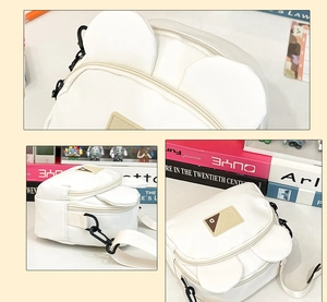 Close-up of a white canvas bear-ear crossbody bag featuring dual zippers and metal hooks
