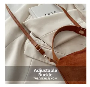 Detail view of brown suede shoulder bag featuring an adjustable gold buckle strap