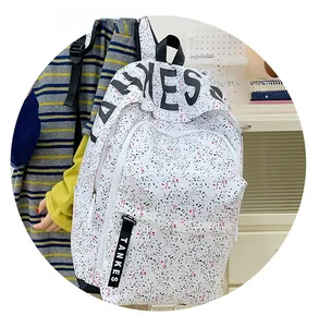 Detail of white polka dot backpack with GES lettering and decorative logo zipper ribbons