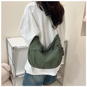 Détail d'un grand sac bandoulière en nylon vert foncé avec nœud de fermeture tissé