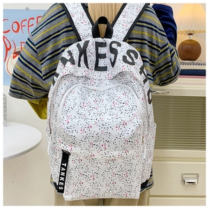 Detail of white canvas backpack with ink splatter dots and black KESS logo print