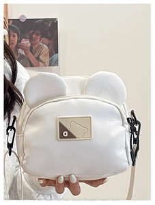 Detail shot of the 3D bear ears and a square logo on a white crossbody canvas bag