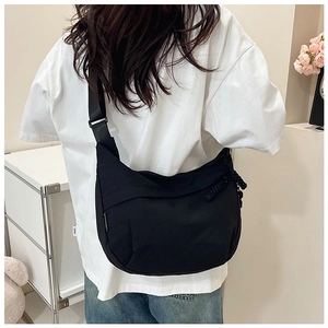 Détail de la bandoulière réglable et du tirette tissée sur un sac croissant noir en nylon