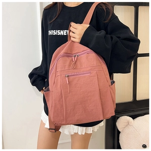 Detail view of water-resistant nylon backpack in dusty pink with multiple zippers