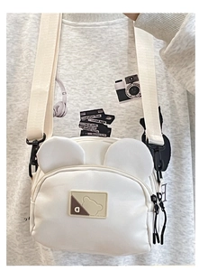 Detailed close-up of a white canvas crossbody bag featuring cute bear ears and adjustable strap
