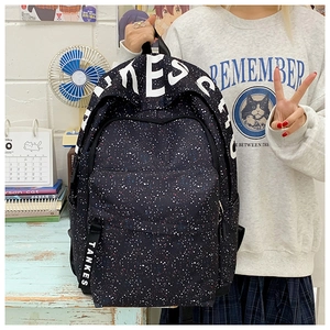 Close-up of black backpack with colorful starry print and bold white typography detail
