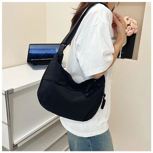 Vue détaillée du sac croissant en nylon noir avec bandoulière réglable et décor de bureau