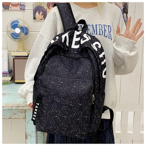 Detail of star-patterned backpack featuring bold white text and hanging strap on canvas