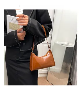 Détails de la finition en cuir verni marron et des boucles métalliques du sac baguette
