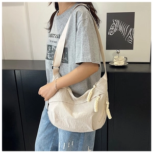 Détail du sac croissant en nylon blanc cassé avec fermeture en corde et bandoulière réglable
